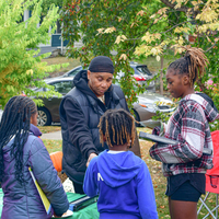 An educator speaks to three youth outdoors