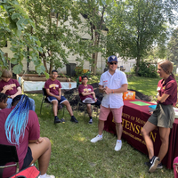 Youth seated outdoors in a circle listening to Extension educators