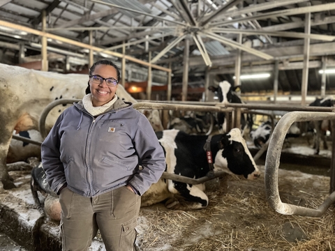 Dana stands in front of three dairy cows smiling