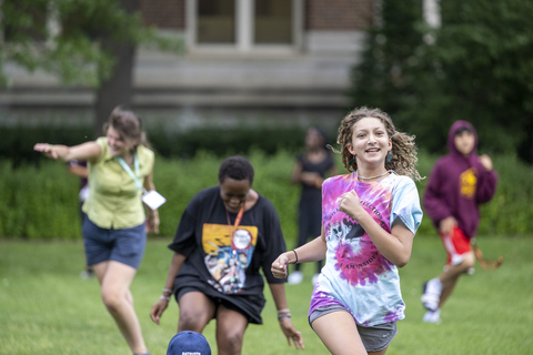 A group of youth running in a grassy area. 