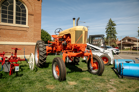 Tractor and bobcat parked on grass outside.