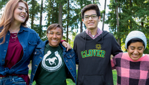 Four teens standing with their arms around each other laughing