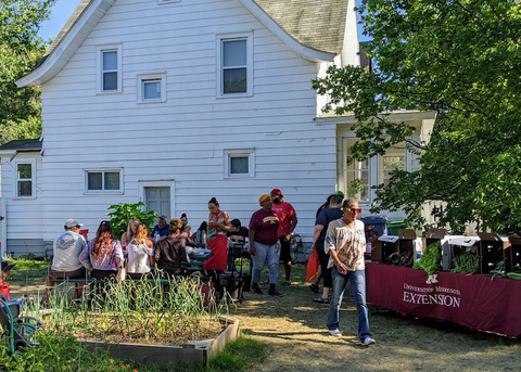 People gathered around a picnic table near raised garden beds