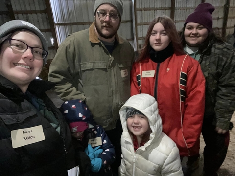 A group of adults and youth smiling at the camera with Allysa Kelton in the foreground wearing a name tag.