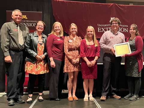 Garden team of six stands on stage, holding an award plaque