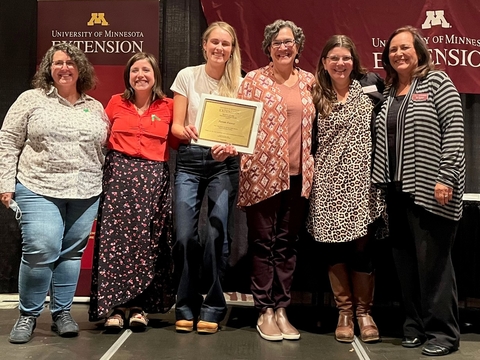 Parents Forever team of five stands on stage next to the dean, holding an award plaque