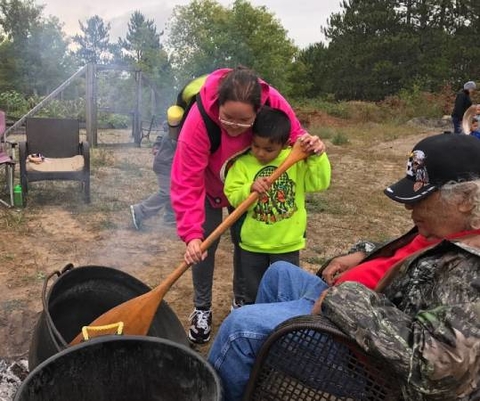 Native American Elders showing children traditional  food from the land.