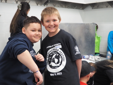 Two boys smiling for the camera. They are wearing their Kids' Groundwater Festival t-shirts.