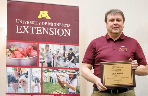 Award winner holding plaque in front of Extension banner