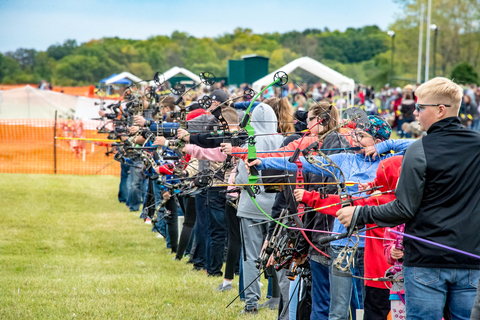 A line of youth aiming bows and arrows.