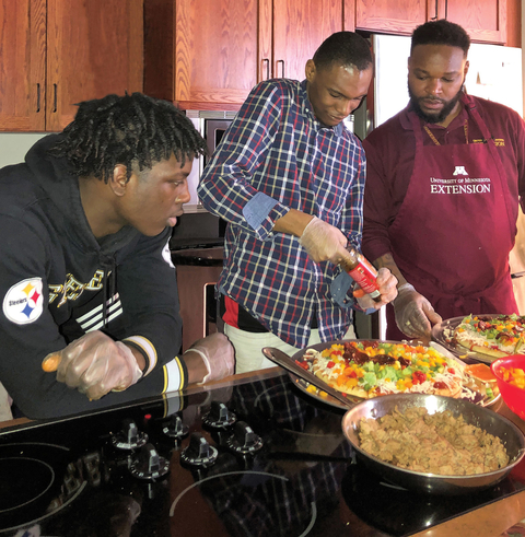 Two teens making pizza with educator Michael Stratten