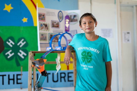 A 4-H'er poses next to a county fair project.