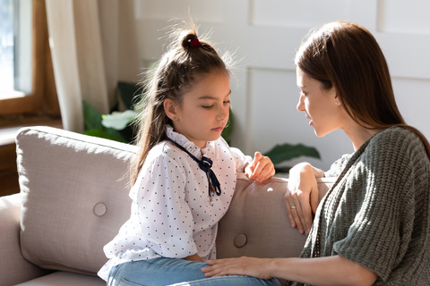 Adult talking to a kid on a couch.