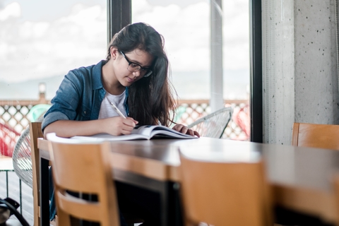 A girl writing in a notebook at a table.