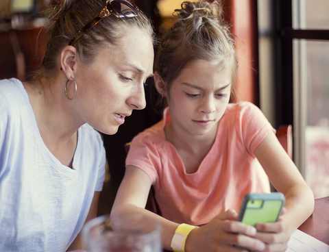 Mother looking at daughter's cell phone