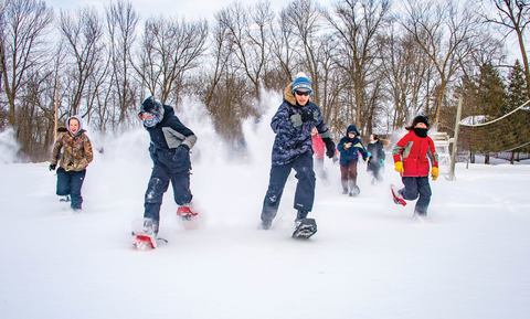 Youth running in snow in snow shoes.