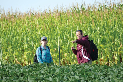 Extension specialist and grad student by cornfield