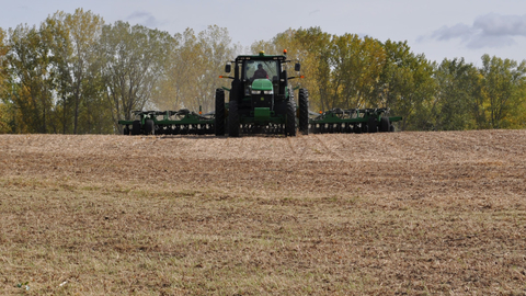 A farmer operating a tractor with disc harrow