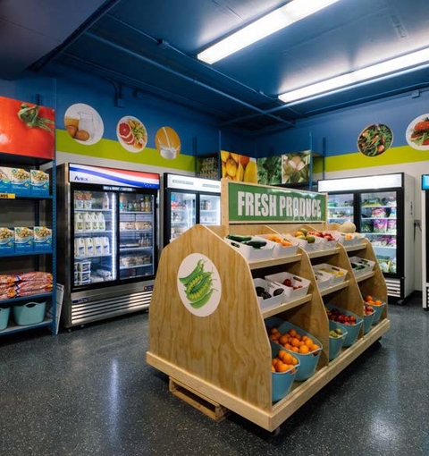 A well-lit, colorful food shelf display contains oranges, dairy and other healthy foods