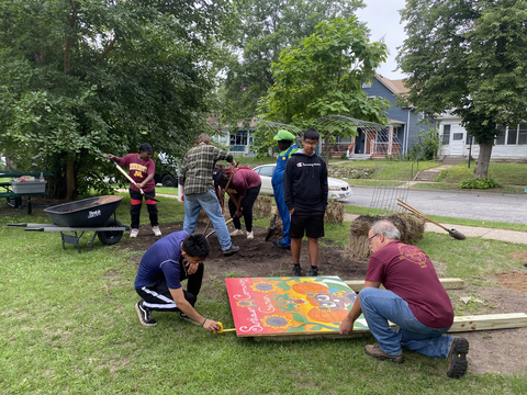 Crew members working on a color painted sign with sunflowers