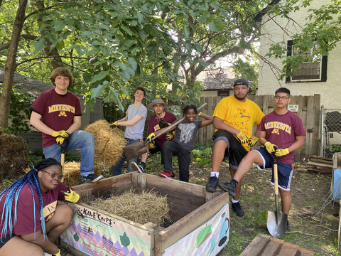 Seven Gardens for Change crew members gathered around a raised garden bed with straw