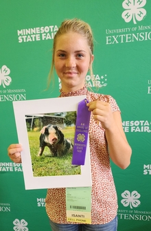 Girl holding photo of pig that is surrounded by water droplets.