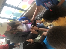 Shot from above, photo shows Abby showing a black chicken to kids who are petting it.