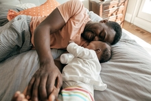 father and baby resting in bed, baby has milk bottle