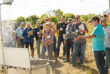 People standing around a board in a field for a presentation