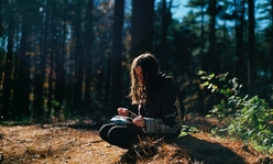 A girl writing in a journal outdoors.