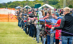 A line of youth aiming bows and arrows.