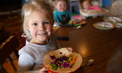 Small girl holding plate with veggie wrap