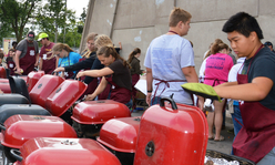 Youth standing around a row of red grills.