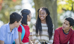 four teens talking in a park