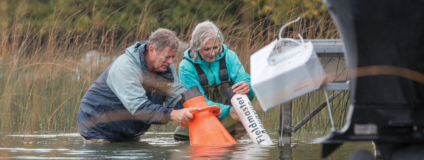 Man and woman in lake collecting water samples