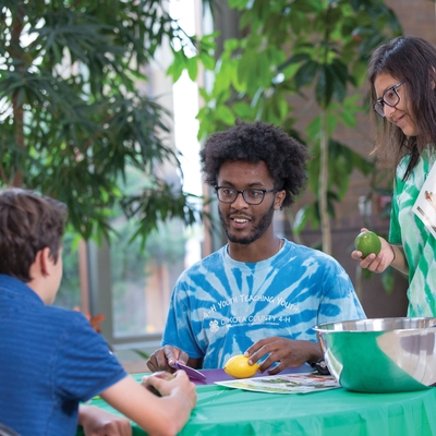 boy and girl teach another youth about cooking with fruit