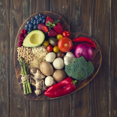 A heart shaped bowl filled with healthy produce and grains