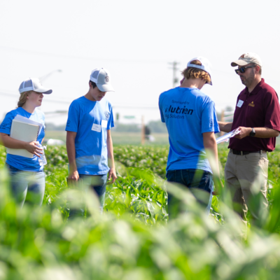 A man is talking to three teen boys in the middle of a field. 