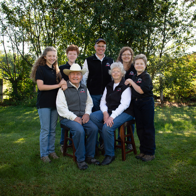 Three generations in one family portrait, with elder couple in front (man wearing cowboy hat), the next generation and their children standing behind