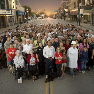 Dozens of community members standing on main street in a small town. 