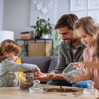 a dad helps two children count coins