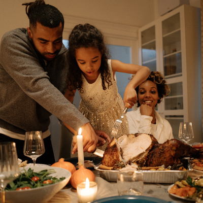 A father and daughter carving a turkey at a dining table