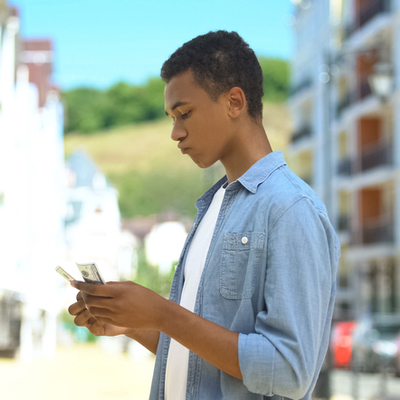 teenage boy counting money on the street