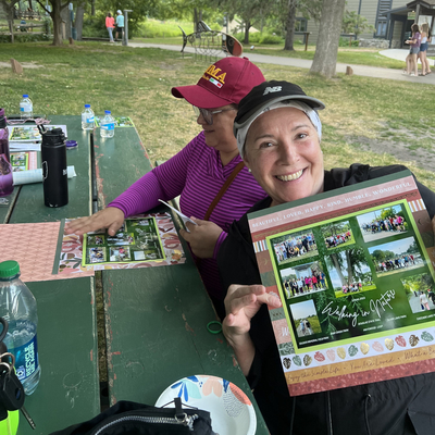 A woman holds a certificate up in a park