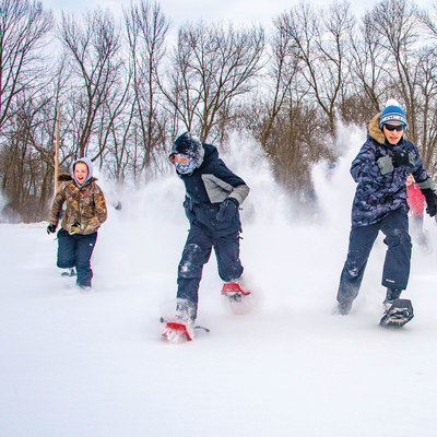 4-H youth running in snow with snow shoes.