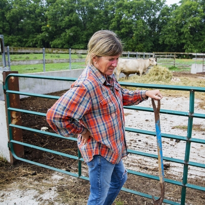 A female farmer with backache outside of a beef cattle pen.