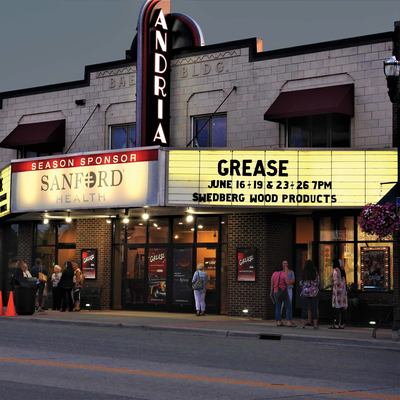 A movie theater at dusk with "Grease" on the display board.